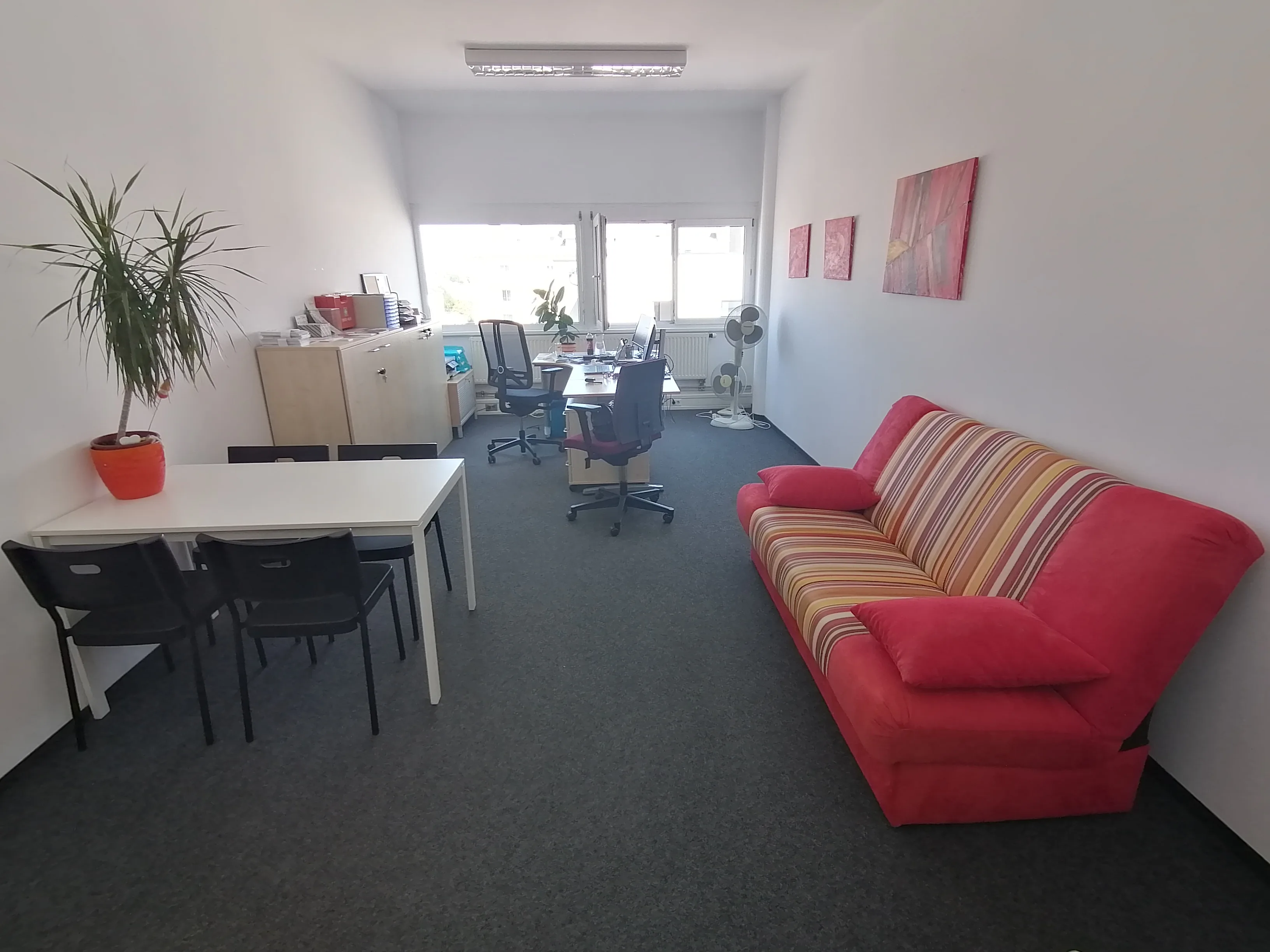 Dasselbe Büro nach dem Möbelmix mit neu geordnetem Arbeitsplatz und roter Couch